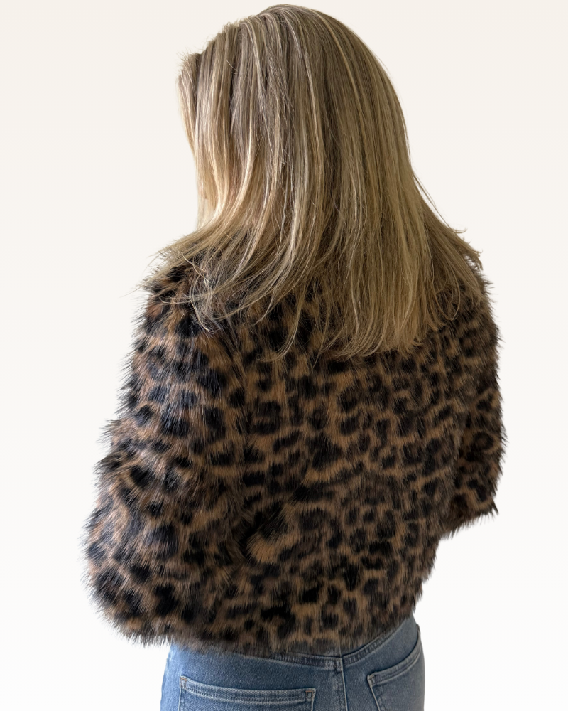 Person wearing a leopard print faux fur jacket on a white background
