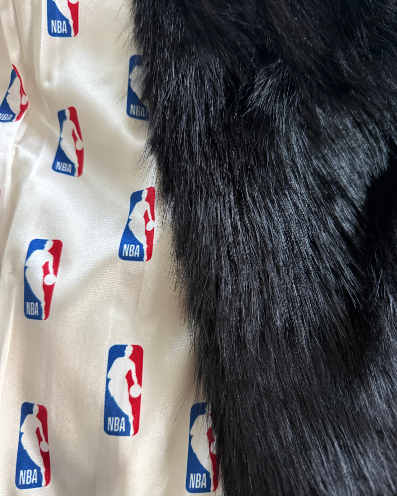 Close-up of a coat with NBA logos and black fur trim.