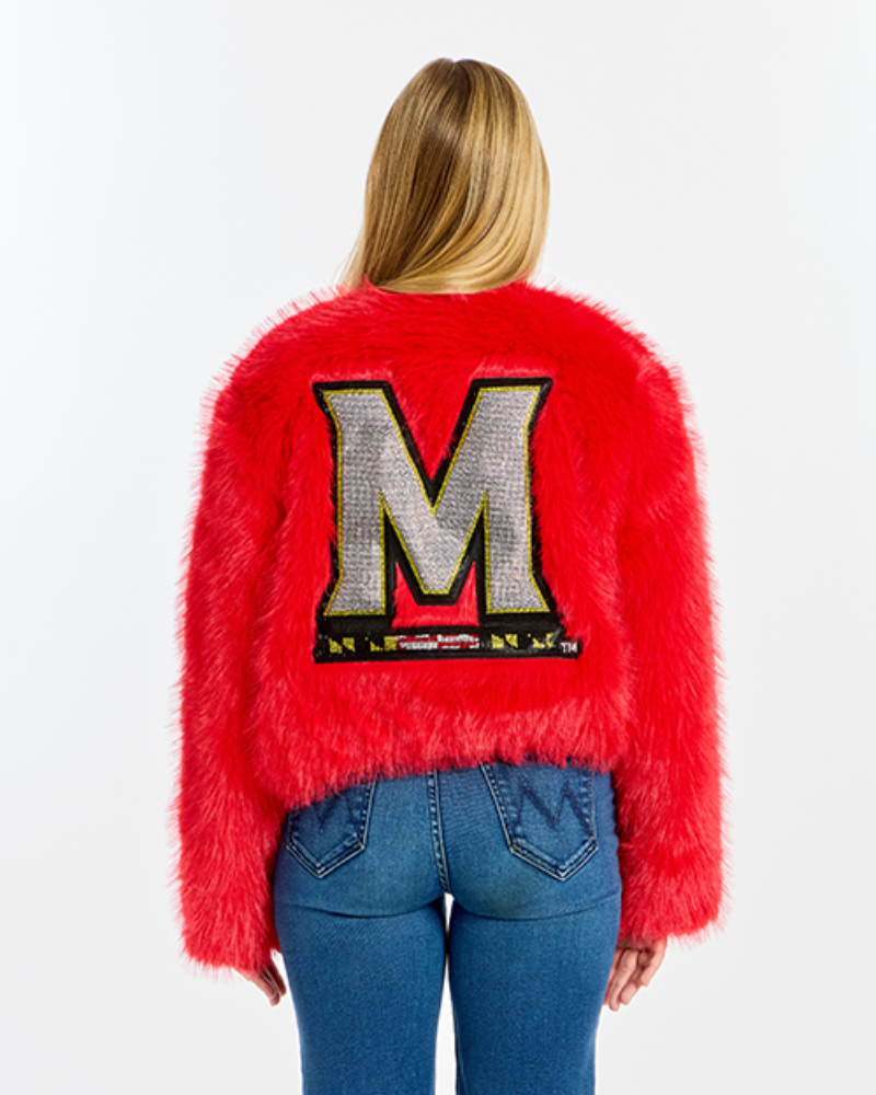 A model viewed from behind wearing a bright red fuzzy cropped sweater with a large bedazzled letter 'M' on the back, paired with blue jeans, against a plain white background.