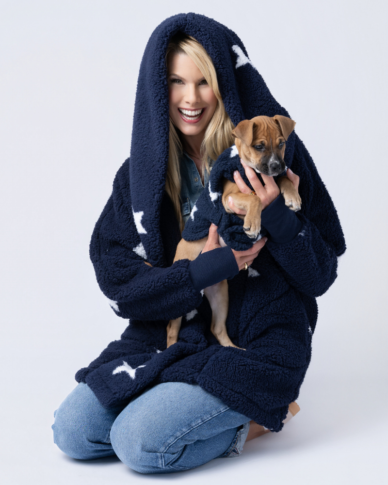 woman wearing navy sherpa with white stars holding dog wearing matching sherpa pet jacket