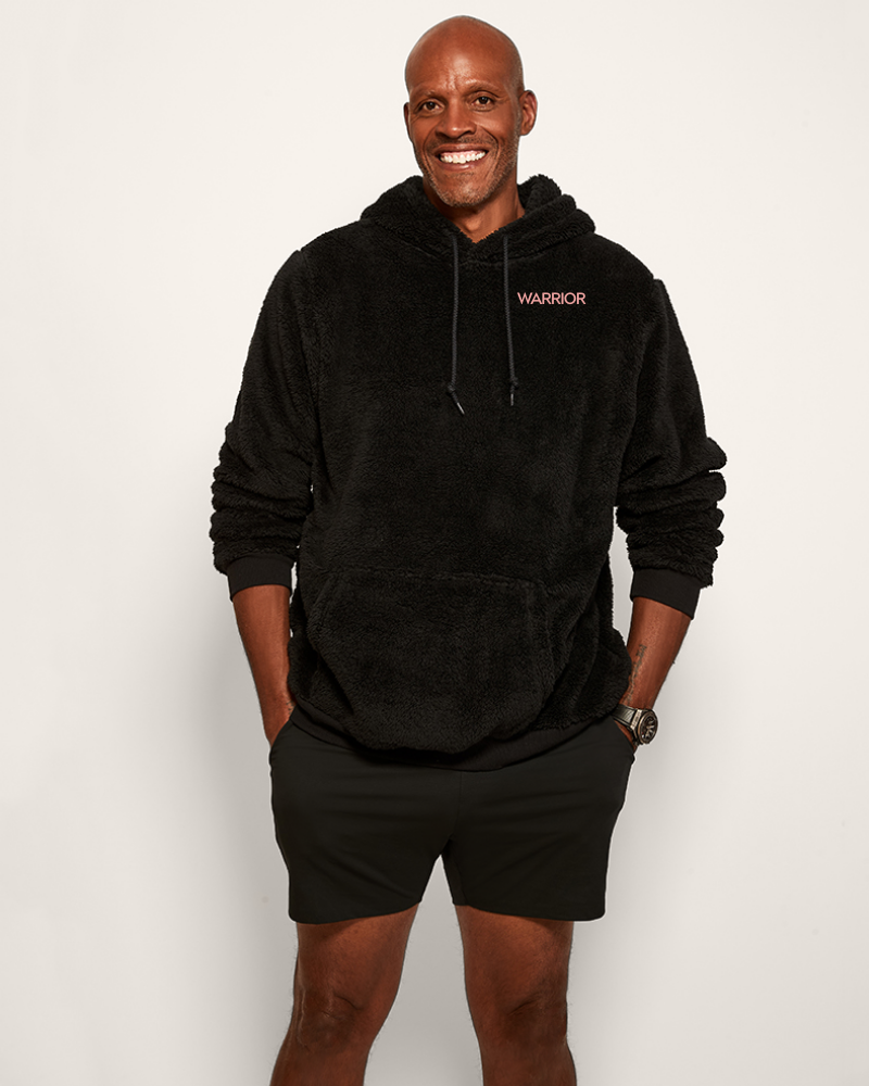 Man wearing a black hoodie with 'Warrior' logo on a white background