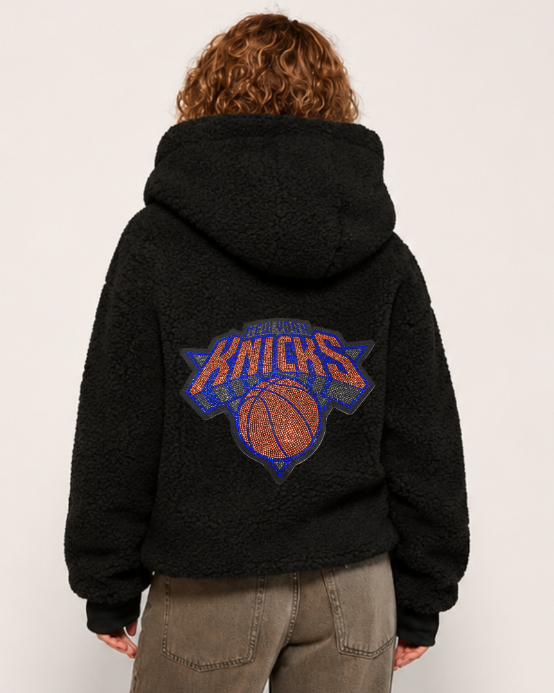 Person wearing a black hoodie with Knicks logo on the back against a white background