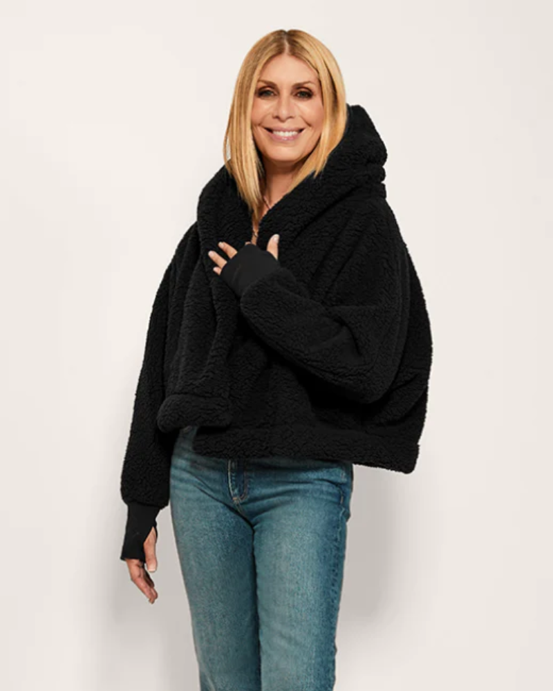 Woman wearing a black hoodie and blue jeans on a white background