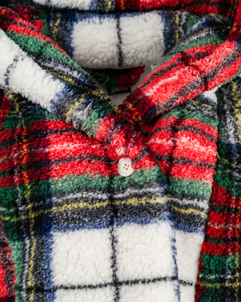 Close-up of a plaid fabric with a button, featuring red, green, and white colors.