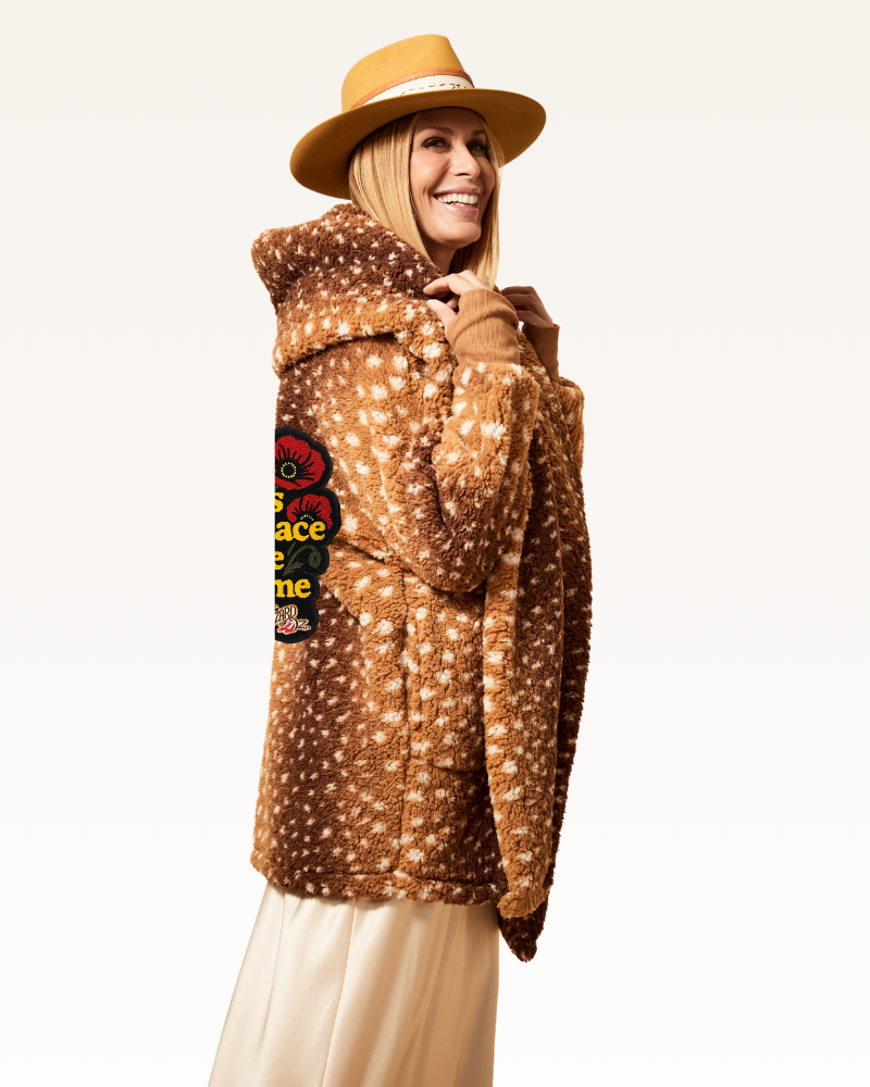 Person wearing a brown patterned jacket with a hood and a hat on a white background