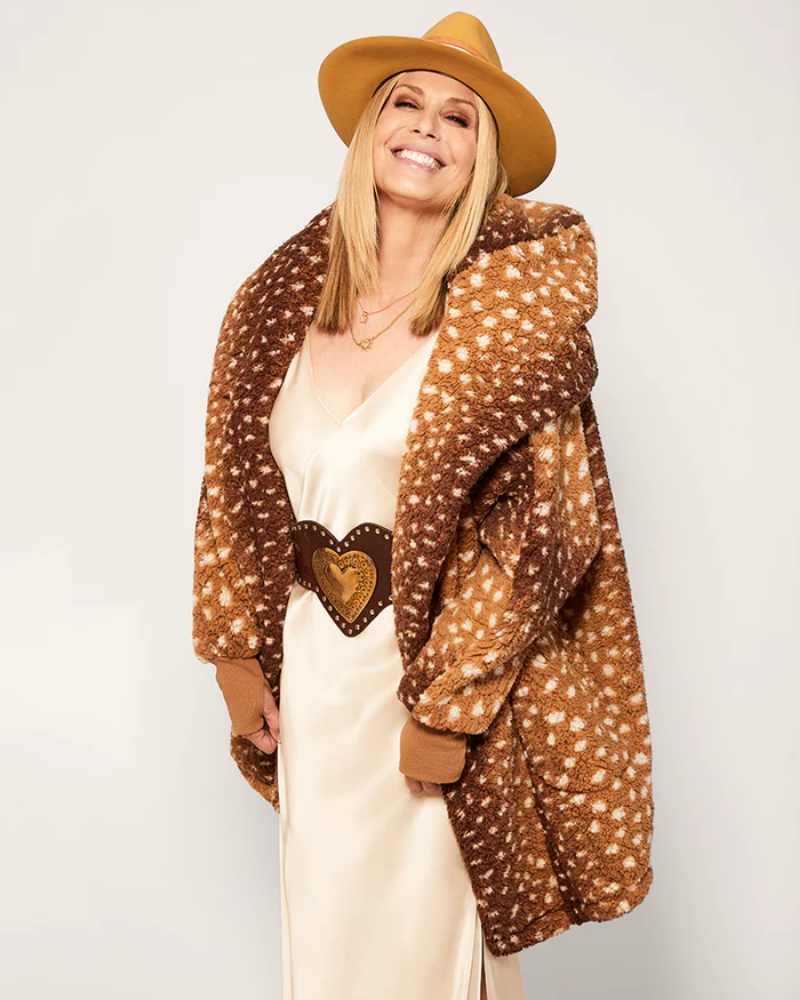 Woman wearing a brown deer print coat, beige hat, and cream dress on a white background