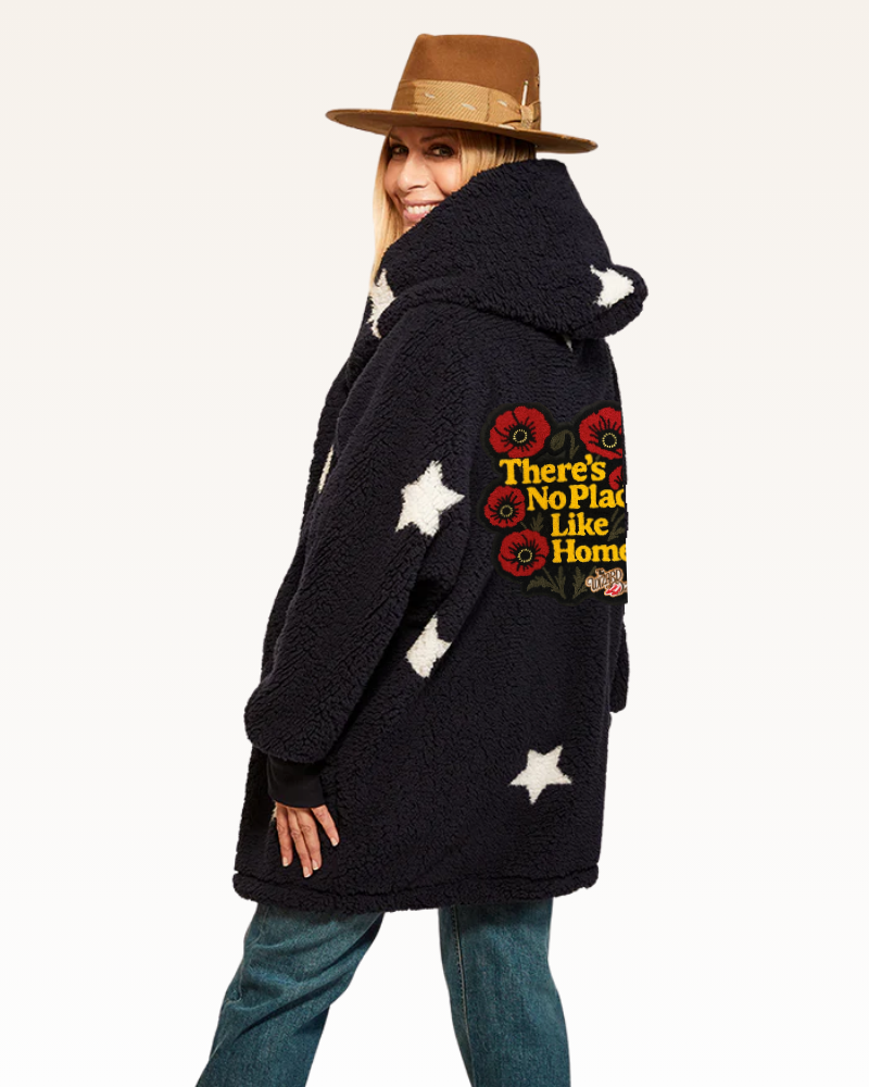 Person wearing a black coat with a quote and star designs, standing against a white background