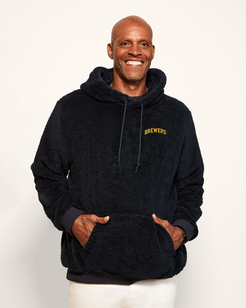 Man wearing a navyhoodie with 'Brewers' logo on a white background