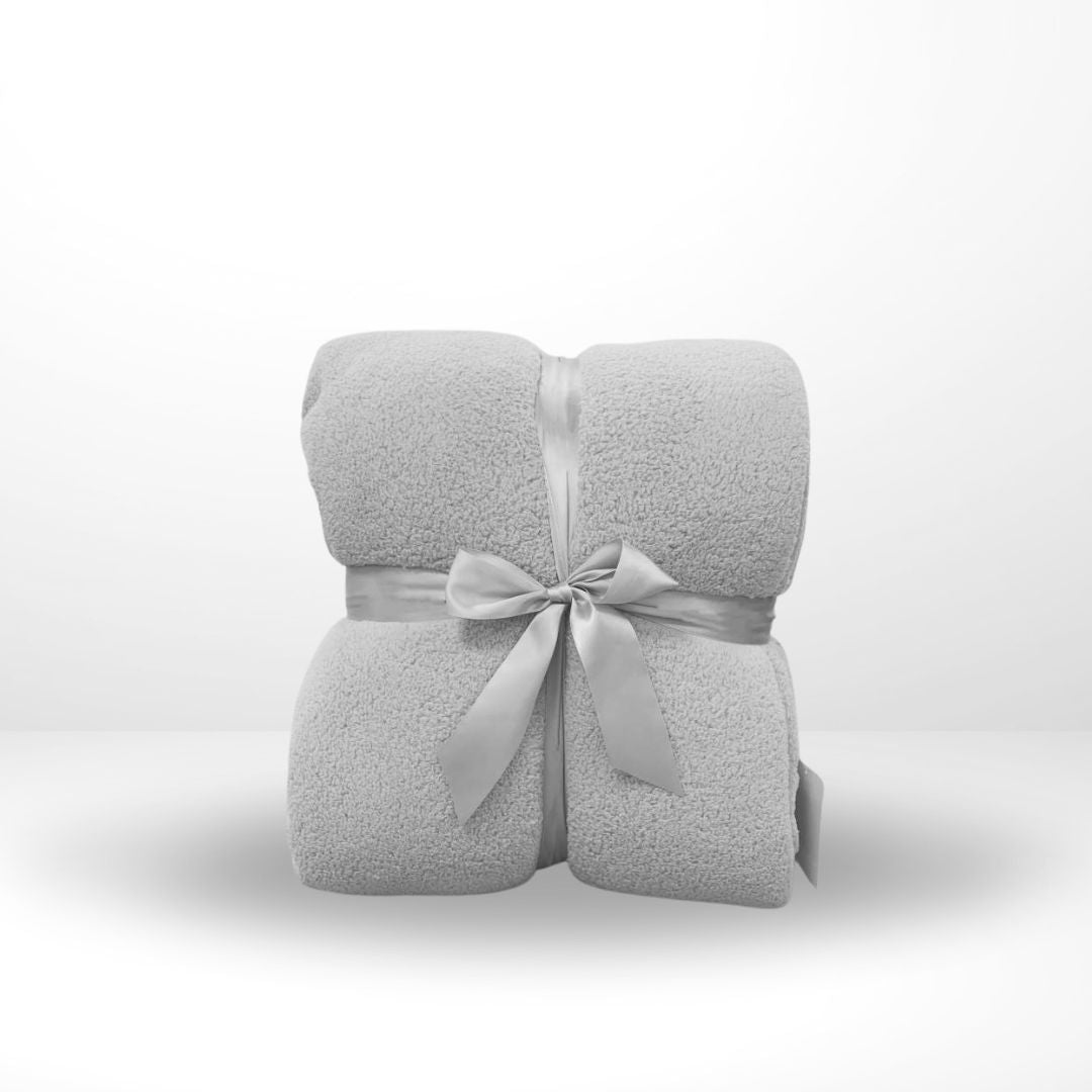 An oversized family blanket in gray, folded and tied with a ribbon in the middle.