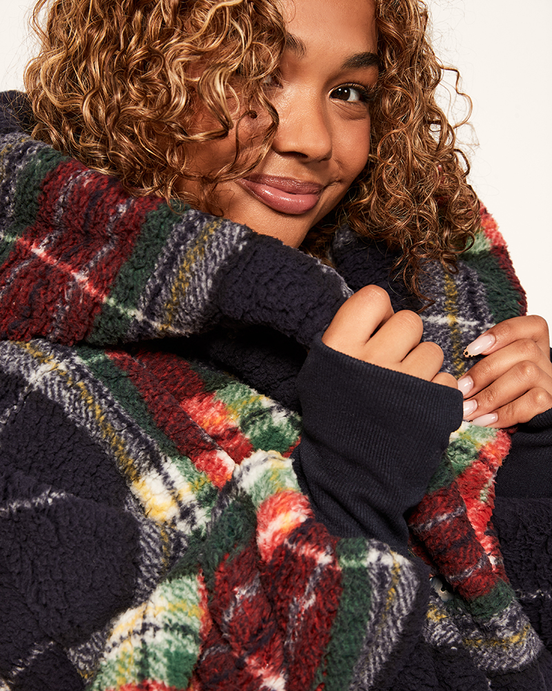 Person wearing a colorful plaid scarf with a neutral background