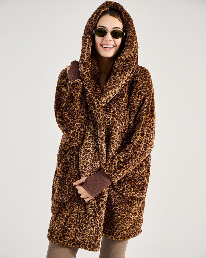 Woman wearing a leopard print coat on a plain background