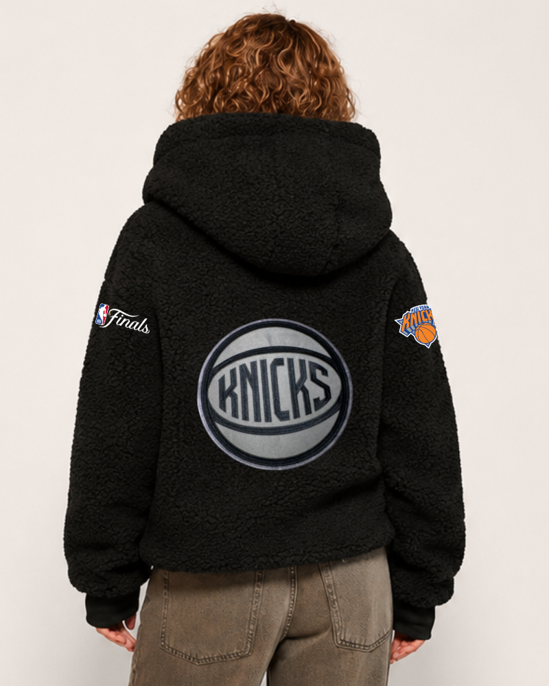 Person wearing a black hoodie with Knicks logo on the back against a white background