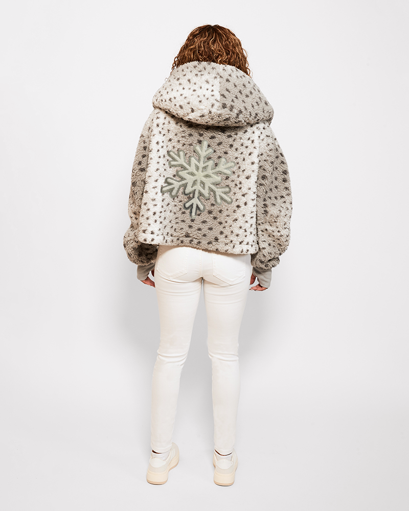 Person wearing a patterned jacket with a snowflake design on a white background