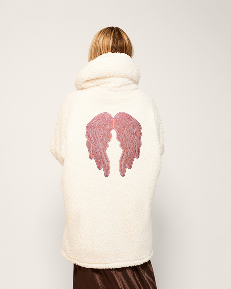 Person wearing a white coat with pink angel wings design on the back against a plain background