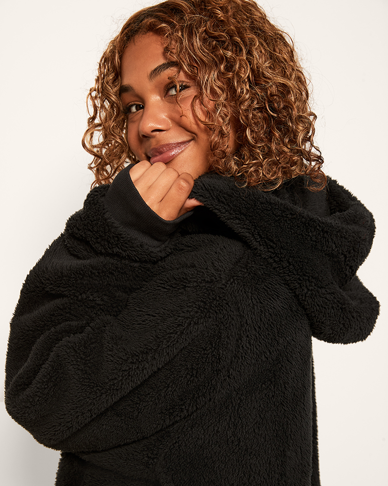 Person wearing a black fleece jacket against a white background