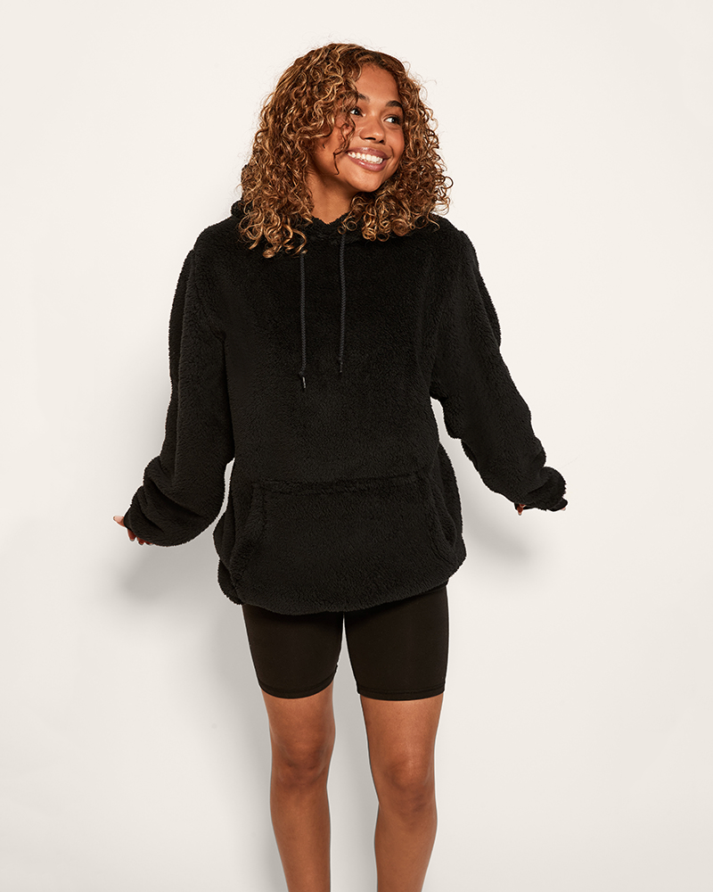 Person wearing a black hoodie and shorts set on a plain background