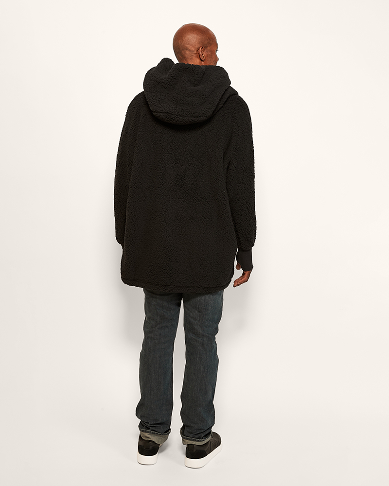 Person wearing a black hoodie and jeans on a white background