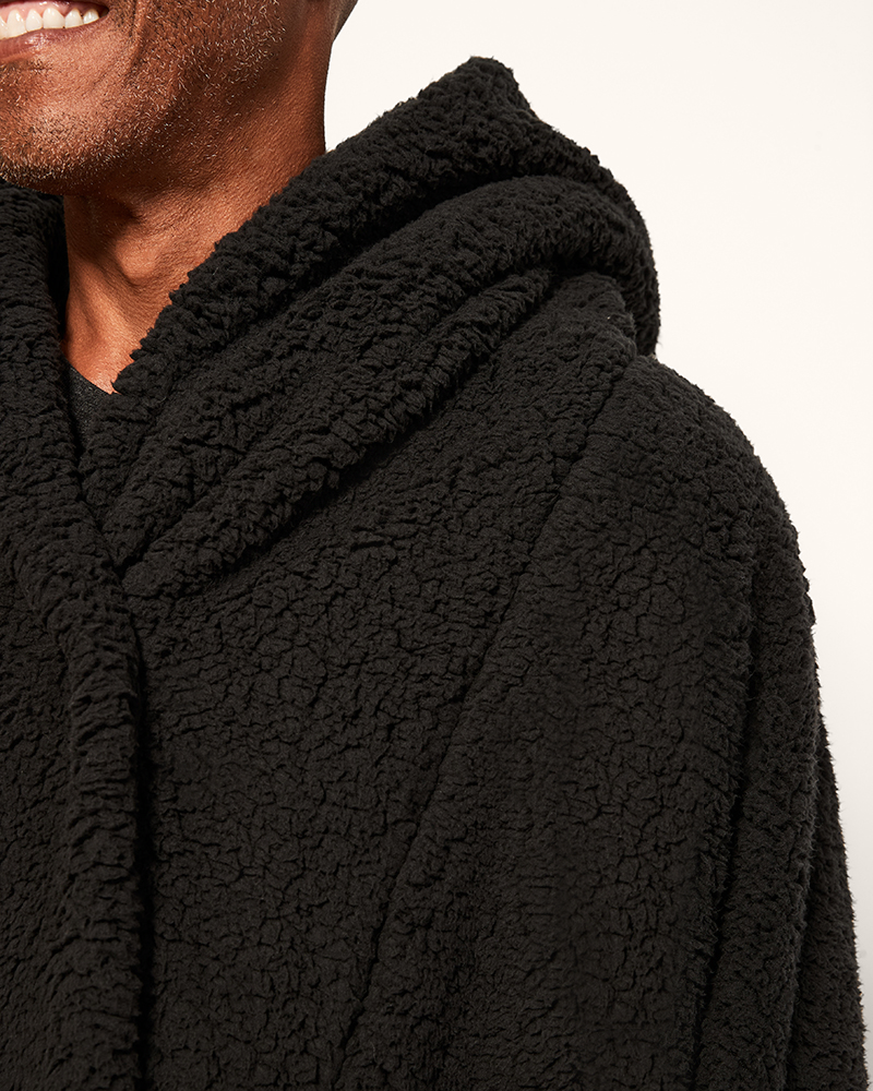 Close-up of a person wearing a black sherpa jacket with a hood.