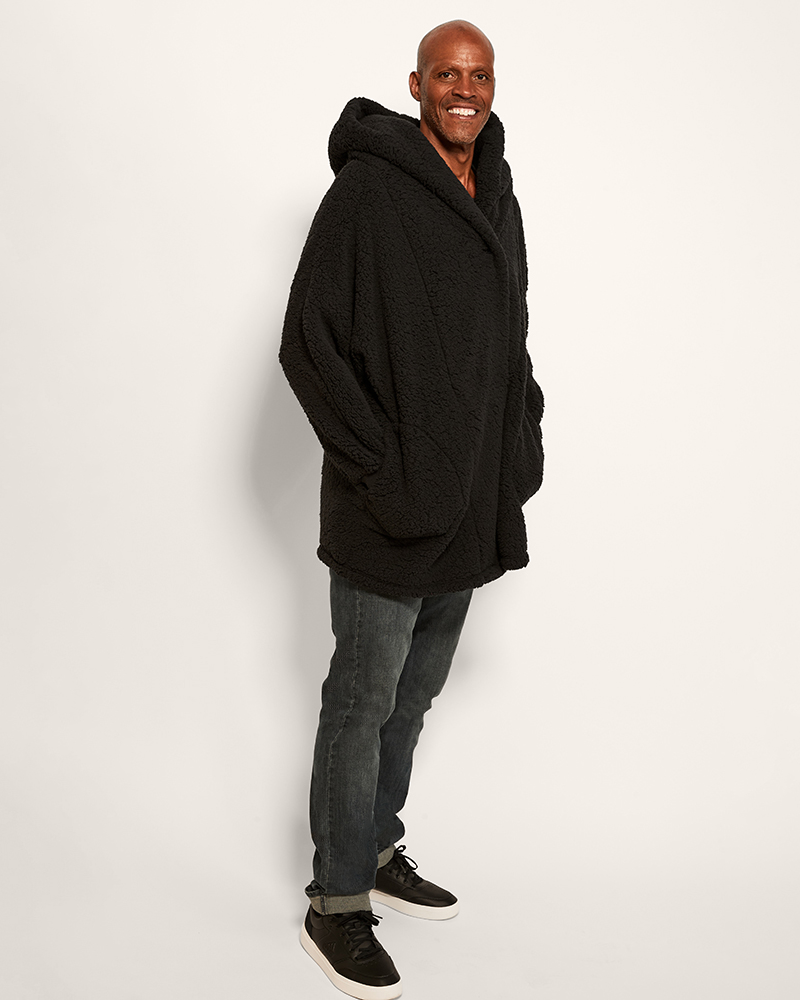 Man wearing a black hoodie and gray pants on a white background