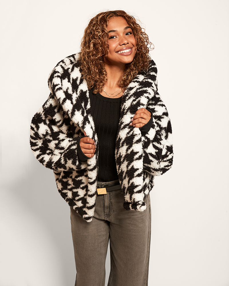 Woman wearing a black and white patterned coat on a plain background