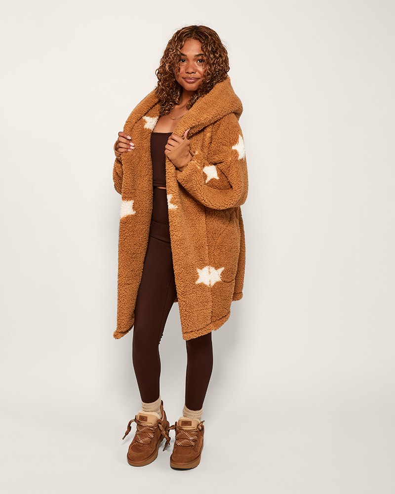 Person wearing a brown teddy coat with star patterns on a white background