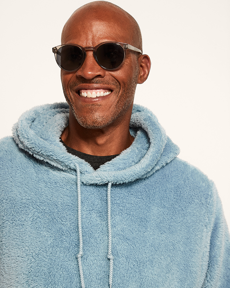 Man wearing a blue fleece hoodie and sunglasses on a white background