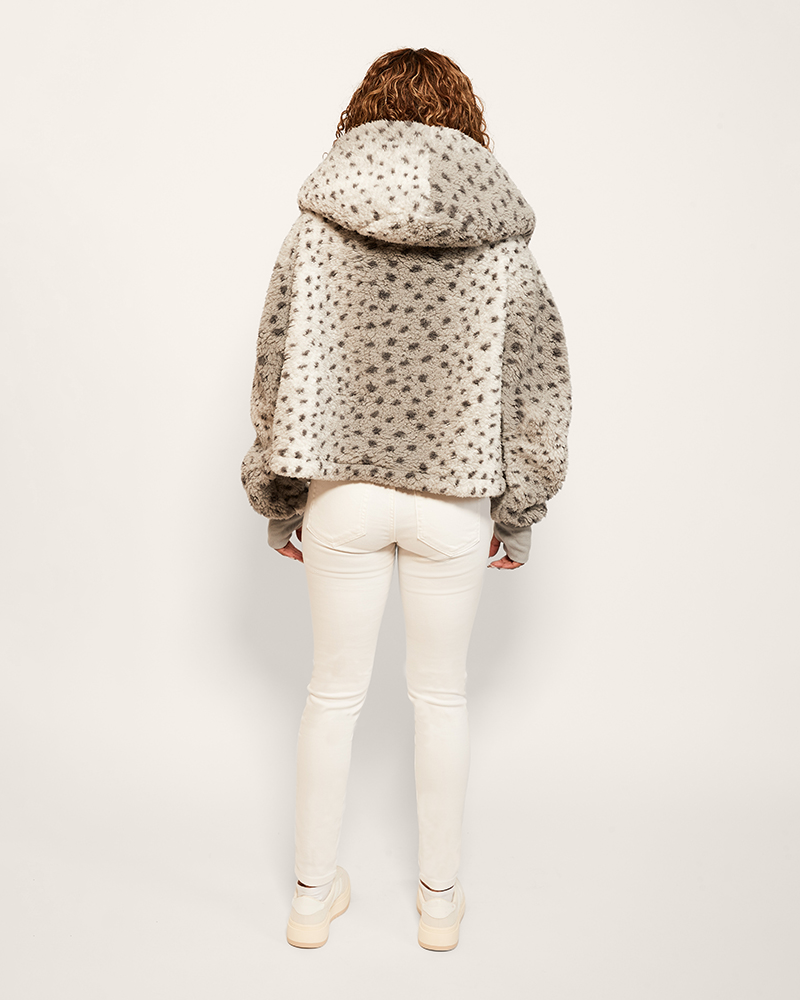Person wearing a patterned jacket and white pants on a plain background