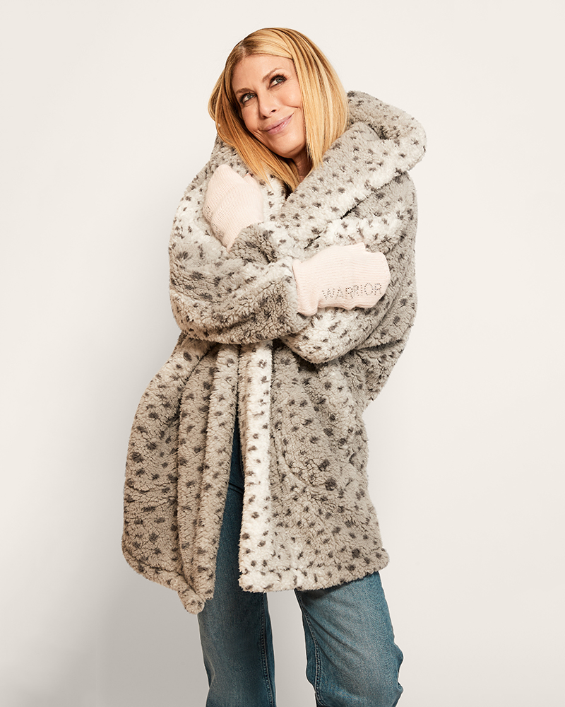 Woman wearing a patterned coat with a hood on a plain background