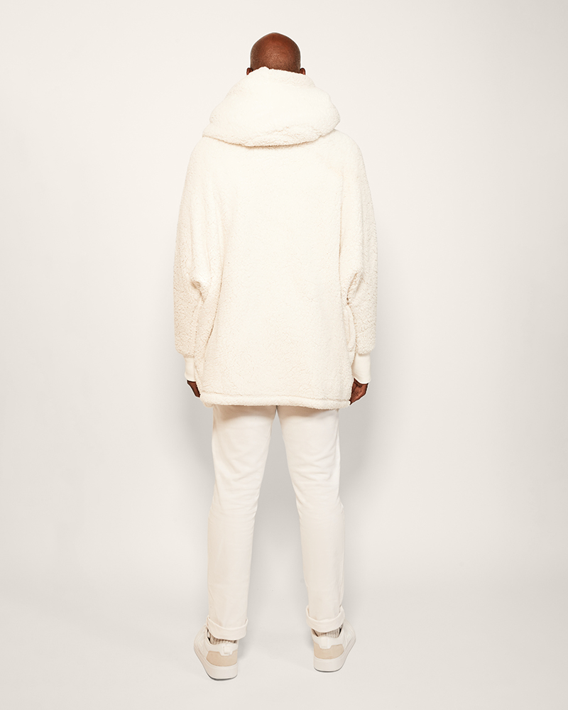 Person wearing a cream-colored jacket and pants on a white background