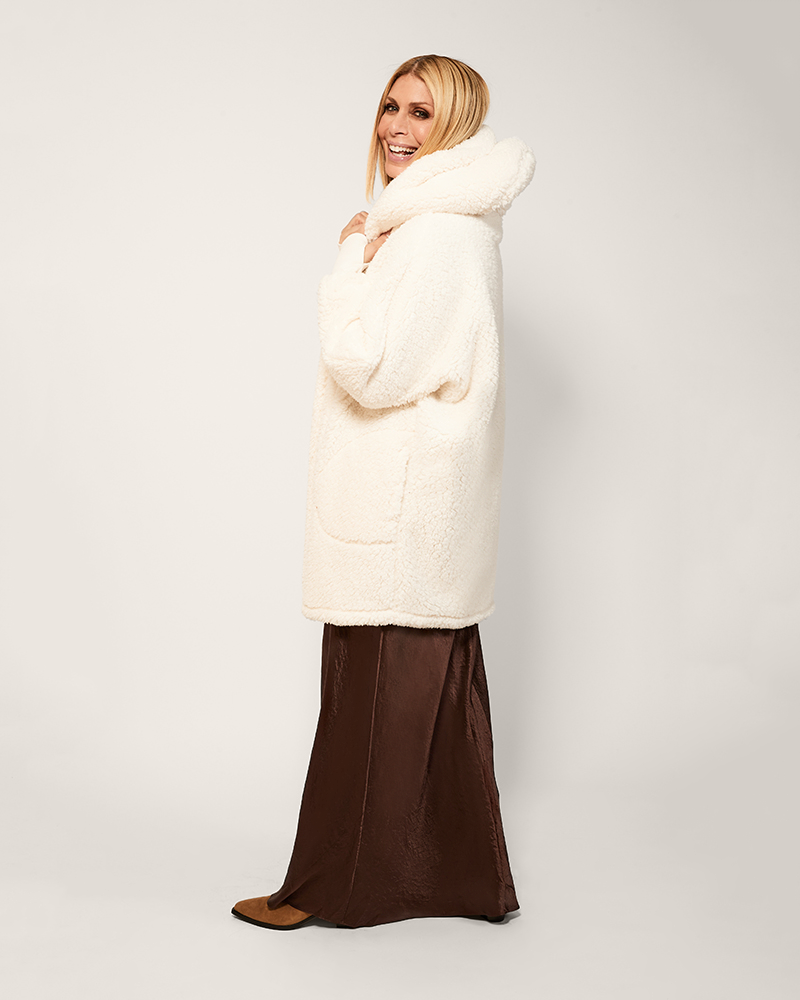 Woman wearing a long white puffer coat against a plain background