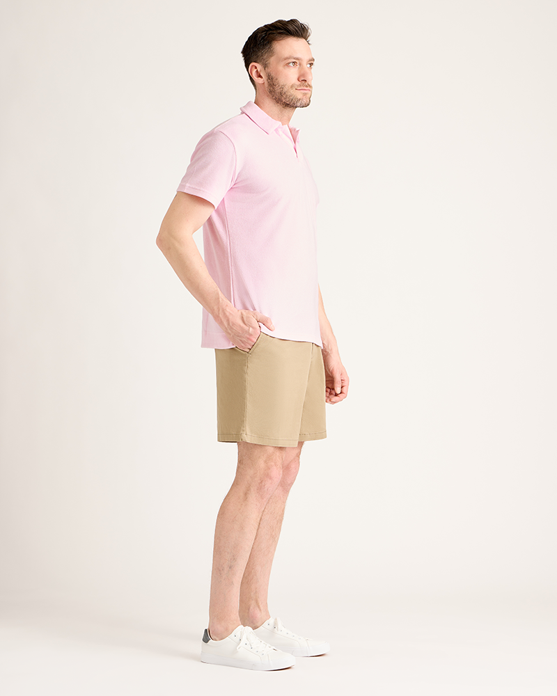 Man wearing a pink polo shirt and beige shorts on a white background|Model: 5'11" wearing size L