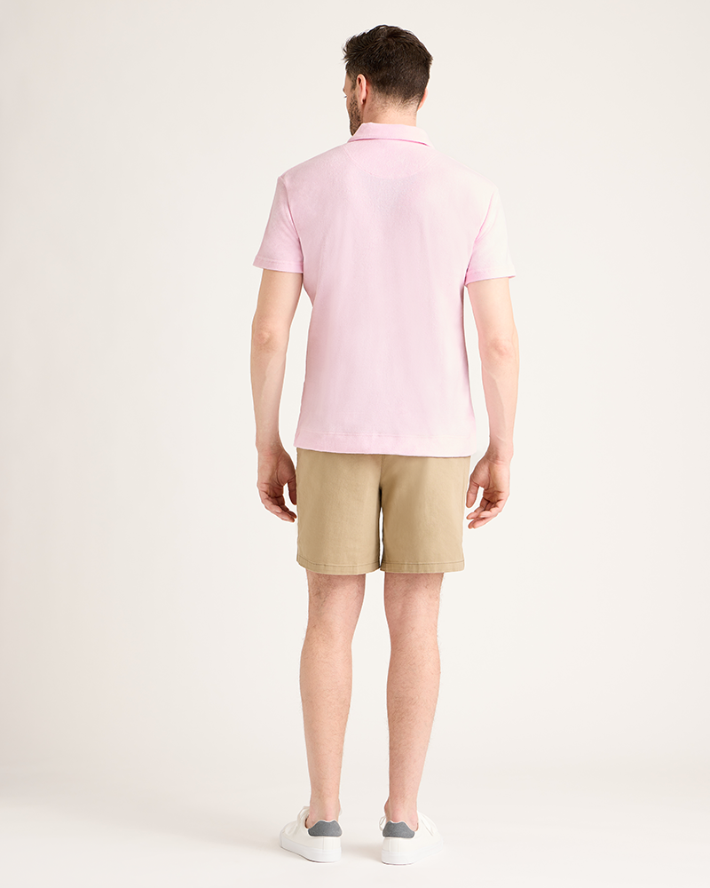 Man wearing a pink polo shirt and beige shorts on a white background|Model: 5'11" wearing size L