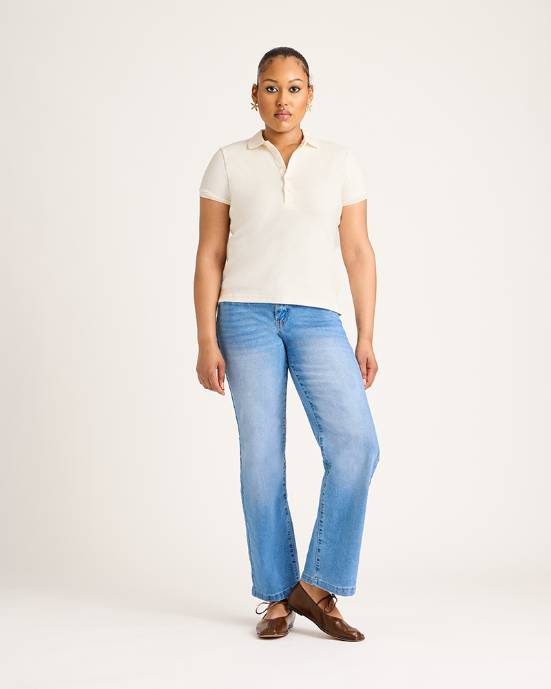 Woman wearing a white polo shirt and light blue jeans on a white background|Model: 5'9 wearing size L