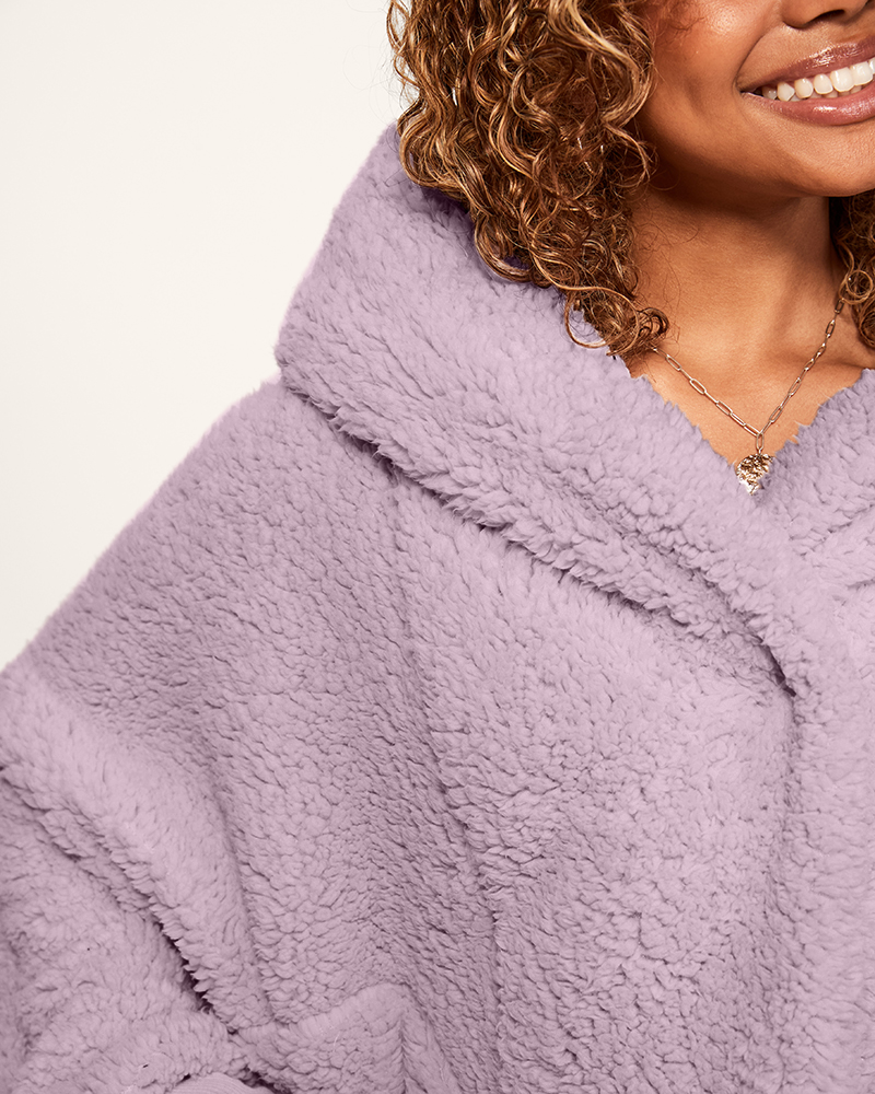 Close-up of a person wearing a soft purple fleece garment with a blurred background