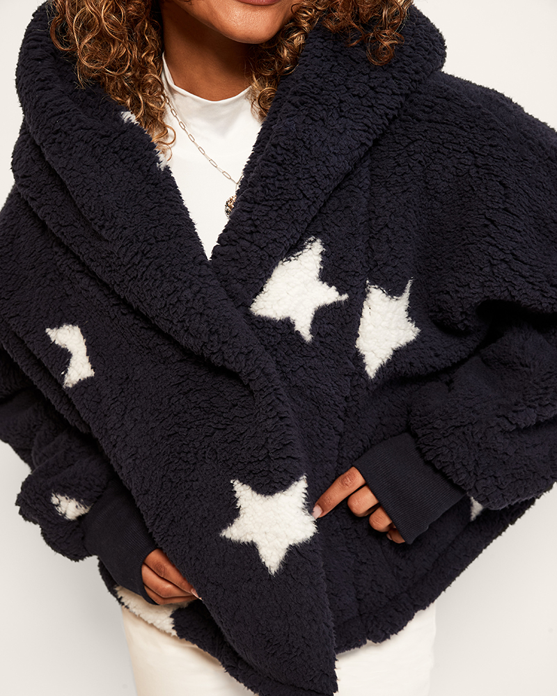 Navy blue poncho with white star patterns worn by a person on a light background