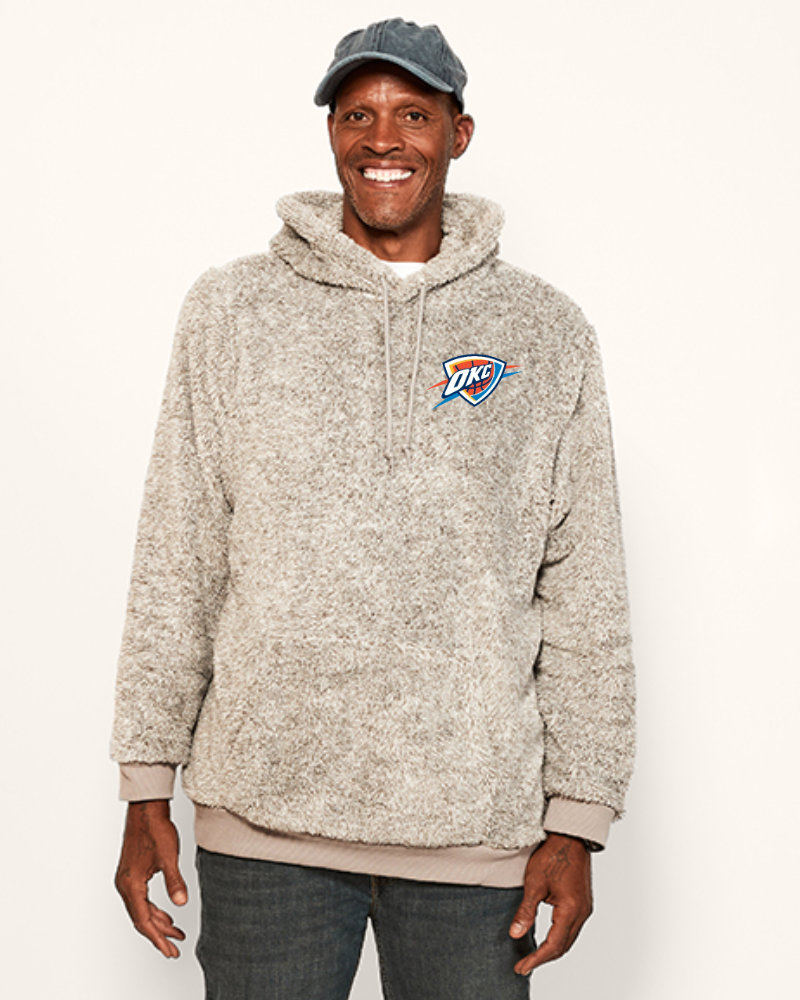 Man wearing a grey hoodie with a oklahoma city thunder logo on a white background