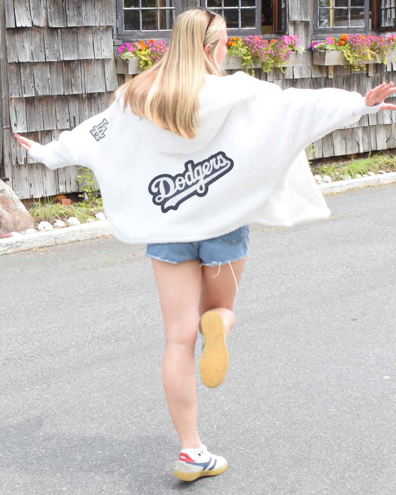 Person wearing a white hoodie with 'Dodgers' logo, running on a road.