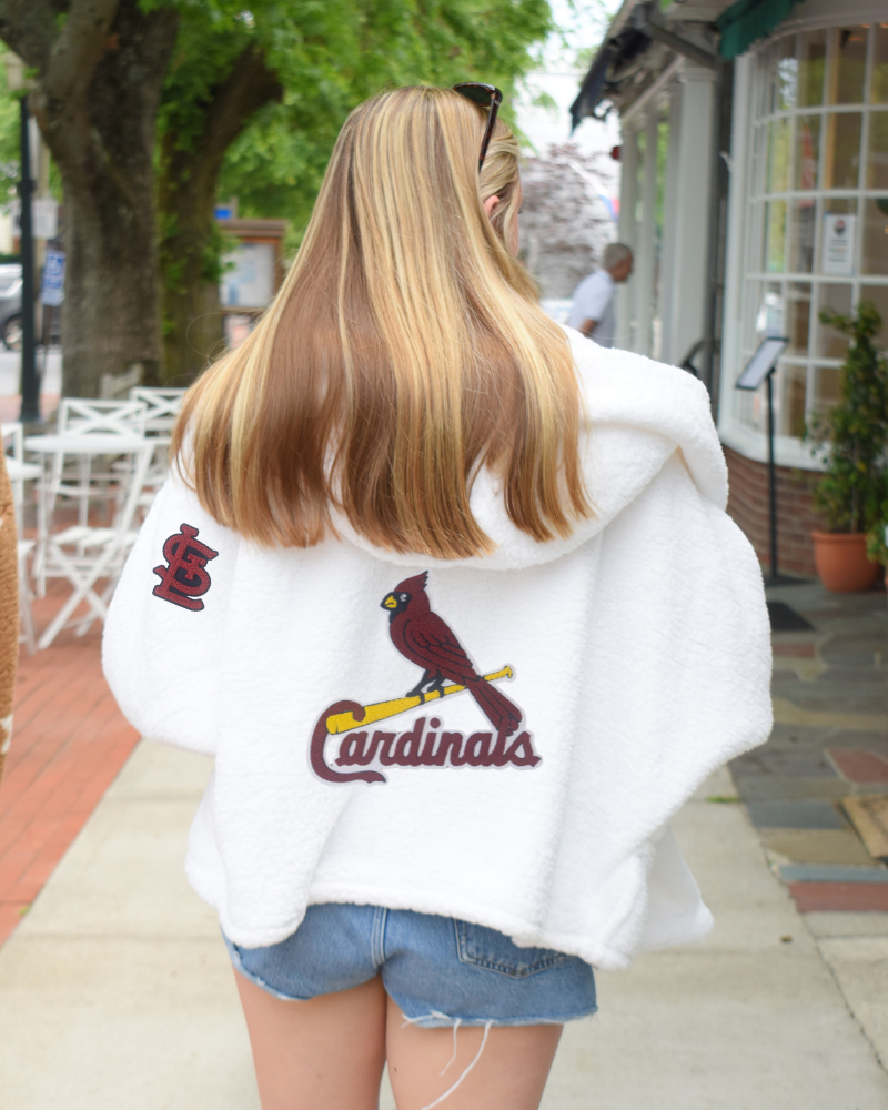 Person wearing a white hoodie with a Cardinals logo outdoors.