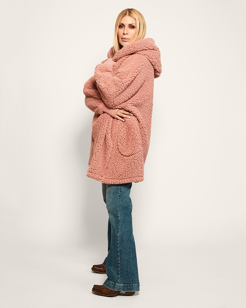 Person wearing a pink hooded coat with a white background