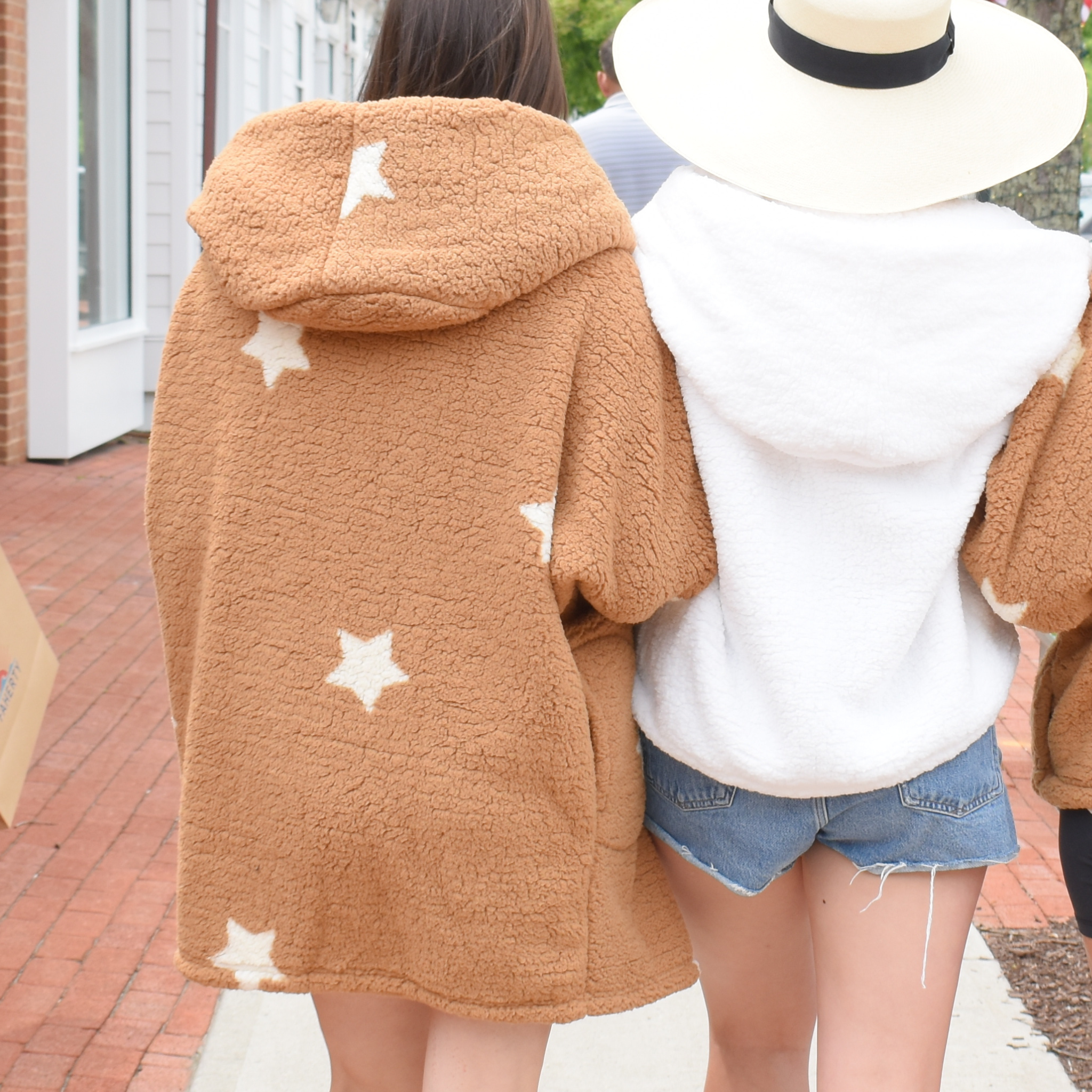 two girls linking arms. girl on right wears oversized sherpa lounger in camel with white start. girl on right wearing white cropped sherpa lounger.