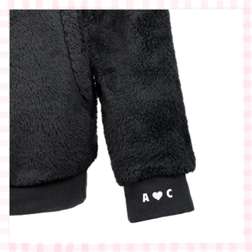 Close-up of a black sherpa sweatshirt cuff with 'A <3 C' stitched in delicate thread.