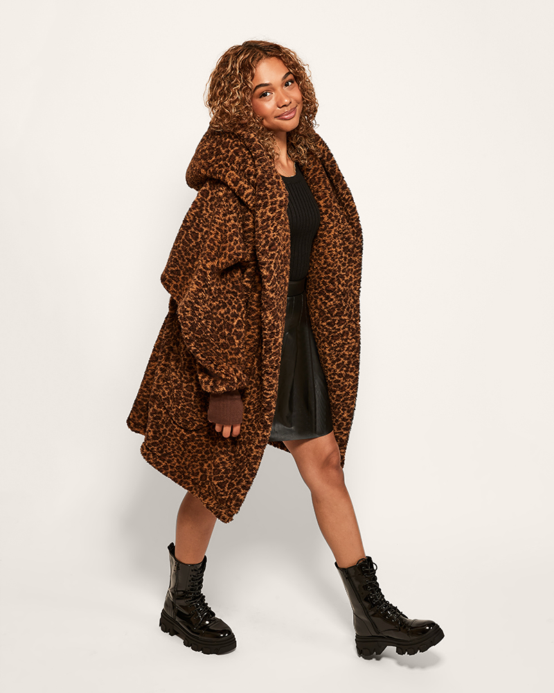 person wearing leopard sherpa lounger over black top and skirt against light background