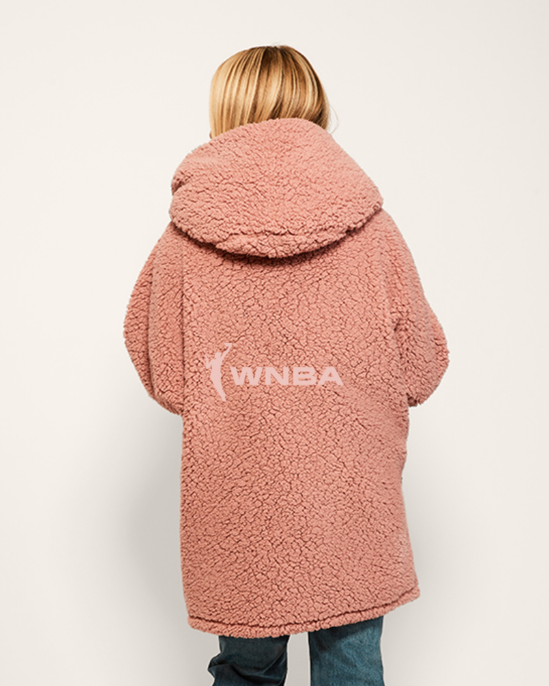Person wearing a pink sherpa coat with WNBA logo on a white background