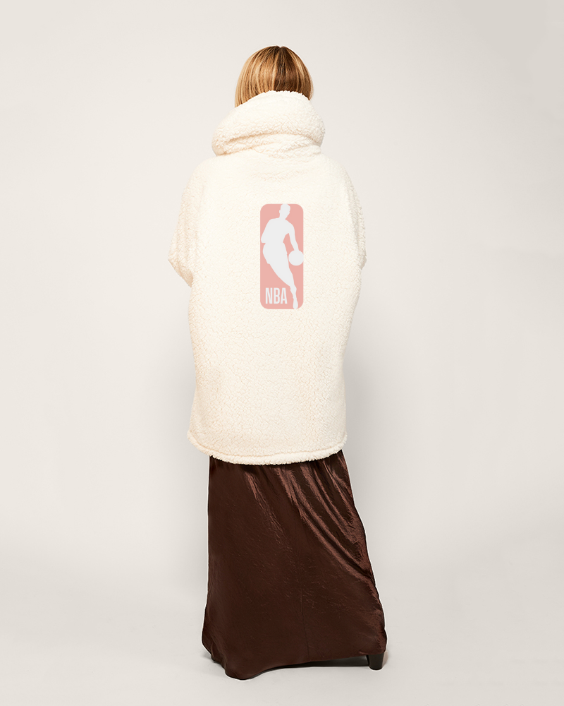 Person wearing a cream-colored jacket with an nba logo on the back against a white background