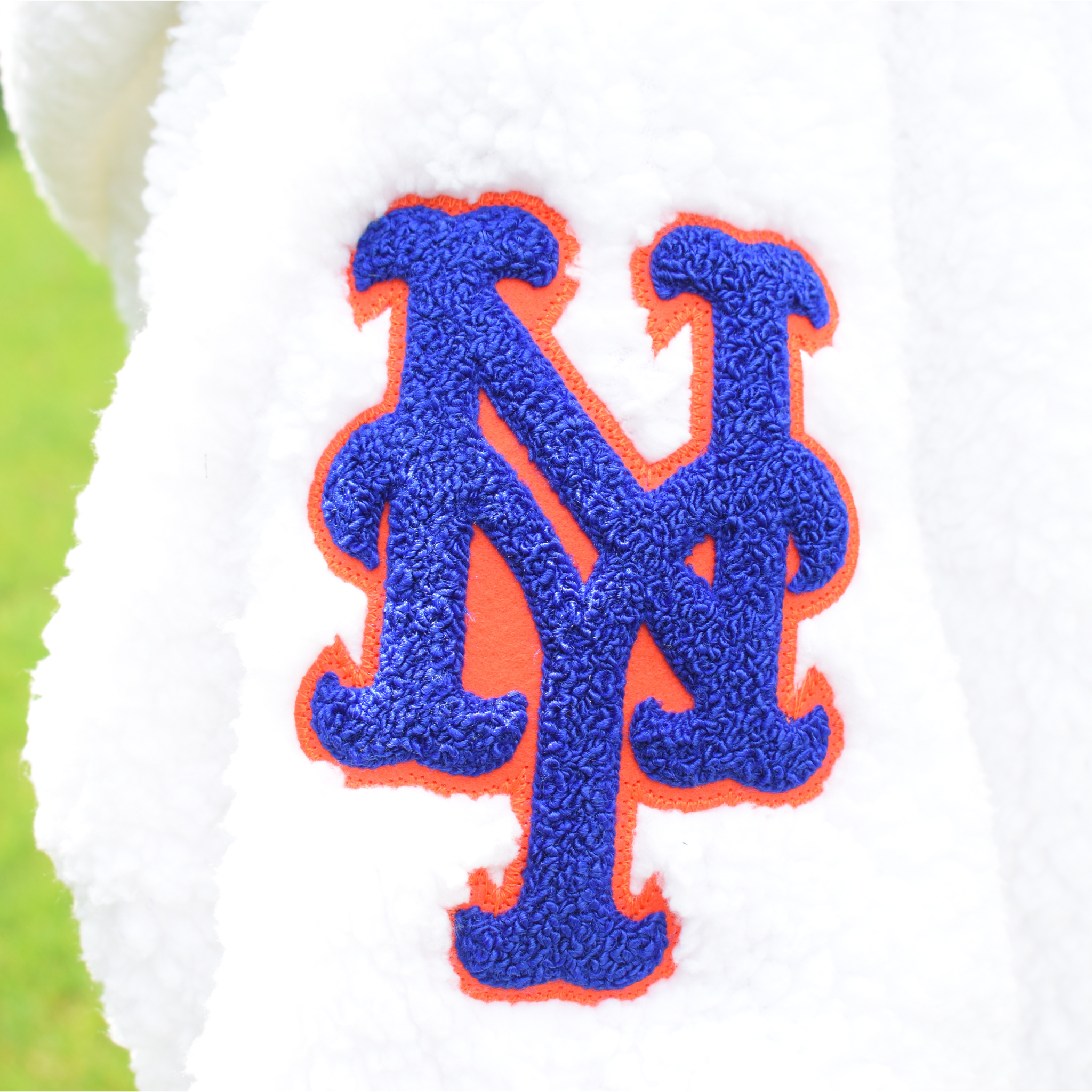 close up photo of ny york mets logo in chenille on the arm of a white sherpa lounger