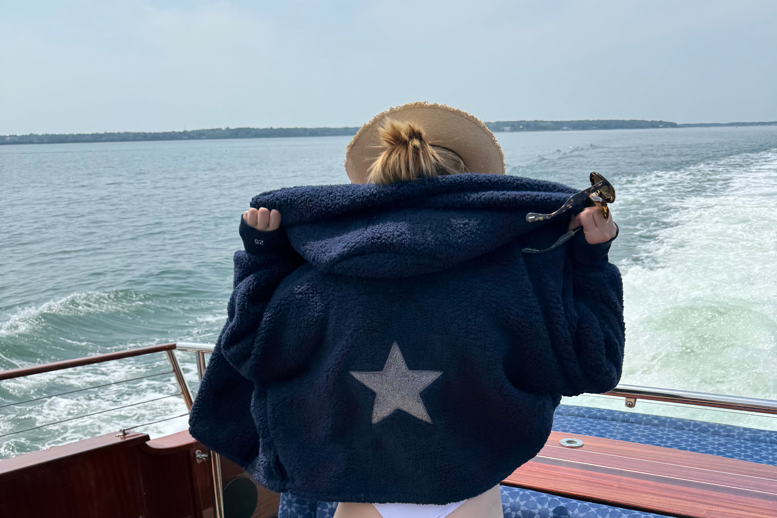 woman on boat wearing navy sherpa cropped lounger with bedazzled star on back