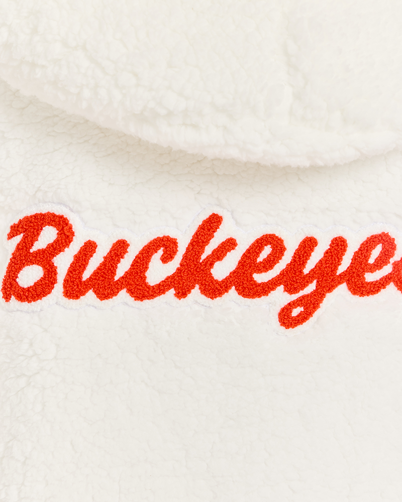 Close-up of a white sherpa fleece garment with red embroidered script reading 'Buckeyes'.