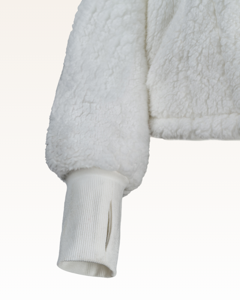 Close-up of a white sherpa jacket with ribbed cuffs on a light gray background