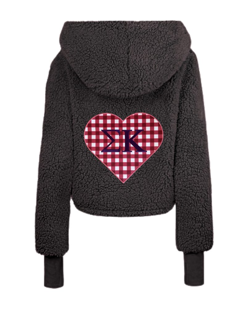 A dark gray sherpa fleece cropped hoodie shown from the back, featuring a red and white gingham heart patch with navy blue Greek letters Sigma Kappa in the center.