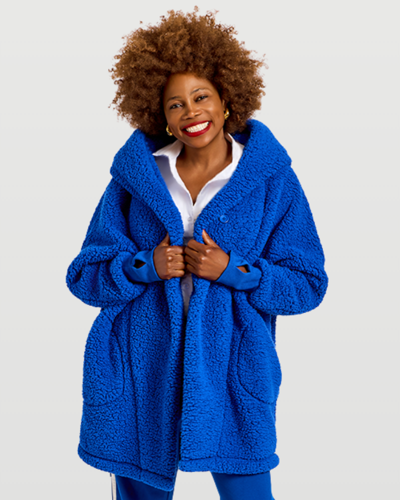 A smiling woman with an afro hairstyle wearing a bright blue sherpa fleece button-up coat over a white collared shirt, photographed against a light gray studio background.|Model is 5'7" wearing size XS/S